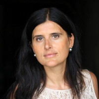 Dark haired woman with a white top on a dark background